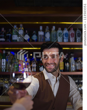Bartender is holding a glass of red wine. Bar, Restaurant, hospitality and beverage,Night club Bartender is holding a glass of red wine. Bar, Restaurant, hospitality and beverage,Night club 113503351