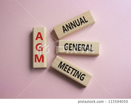 AGM - Annual general meeting symbol. Concept word AGM on wooden blocks. Beautiful pink background. Business and AGM concept. Copy space. 113504050