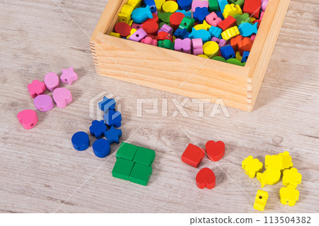Hands of baby playing thread and wooden beads used to making bracelets Hands of baby playing thread and wooden beads used to making bracelets 113504382