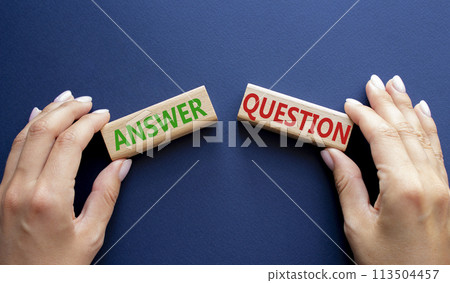 Answer or Question symbol. Concept word Answer or Question on wooden blocks. Businessman hand. Beautiful deep blue background. Business and Answer or Question concept. Copy space 113504457