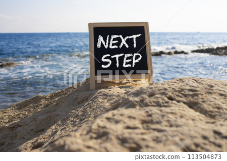 Next Step symbol. Concept words Next Step on black chalk background. Beautiful sea background. Business and Next Step concept. Copy space. Next Step symbol. Concept words Next Step on black chalk background. Beautiful sea background. Business and Next Step concept. Copy space. 113504873