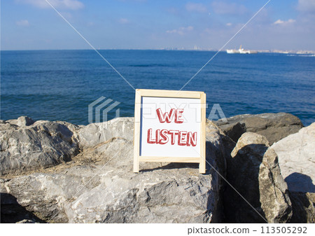 We listen symbol. Concept words We listen on white chalk background. Beautiful sea background. Business and We listen concept. Copy space. 113505292