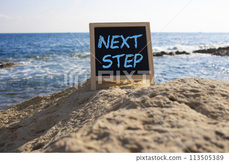 Next Step symbol. Concept words Next Step on black chalk background. Beautiful sea background. Business and Next Step concept. Copy space. Next Step symbol. Concept words Next Step on black chalk background. Beautiful sea background. Business and Next Step concept. Copy space. 113505389