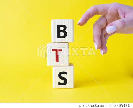 BTS symbol. Wooden cubes with word BTS. Businessman hand Beautiful yellow background. BTS concept. Copy space. BTS symbol. Wooden cubes with word BTS. Businessman hand Beautiful yellow background. BTS concept. Copy space. 113505426