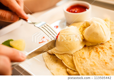 Eating pancake with ice cream and strawberry sauce 113505442
