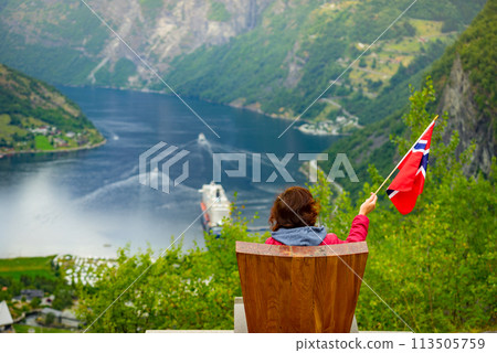 Tourist over Geirangerfjord holds norwegian flag 113505759