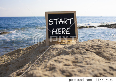 Start Here symbol. Concept word Start Here on black chalk background. Beautiful sea background. Business and Start Here concept. Copy space Start Here symbol. Concept word Start Here on black chalk background. Beautiful sea background. Business and Start Here concept. Copy space 113506030