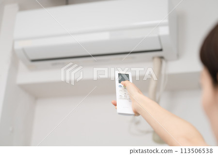一位年輕女性用遙控器改變空調溫度的生活方式形象 113506538