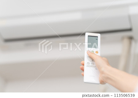 一位年輕女性用遙控器改變空調溫度的生活方式形象 113506539