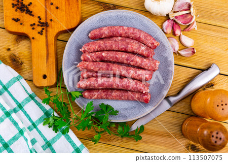 Raw pork longaniza ready for grilling on plate with condiments and greens Raw pork longaniza ready for grilling on plate with condiments and greens 113507075