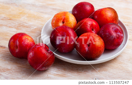 Sweet red plums on wooden table 113507247