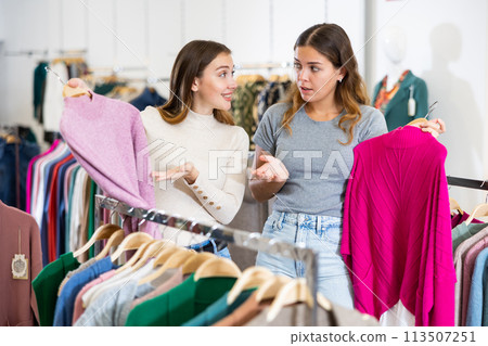 Two cheerful women shopping in outerwear clothing boutique 113507251