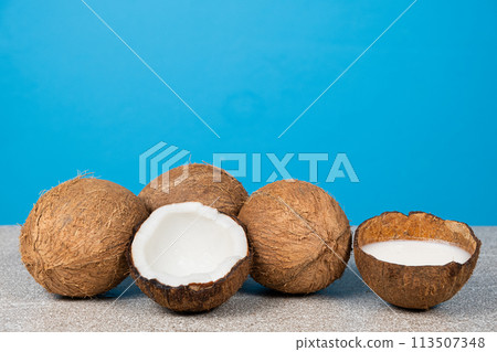 Lots of coconuts on blue background, coconut milk in shell, space for text. Lots of coconuts on blue background, coconut milk in shell, space for text. 113507348
