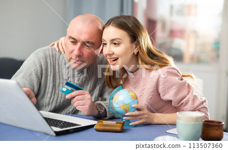 Happy married couple book a vacation tour on a laptop Happy married couple book a vacation tour on a laptop 113507360