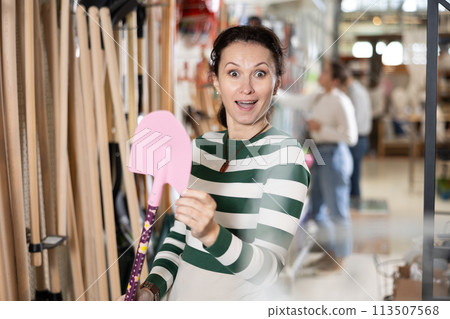 Amateur gardener woman selects necessary items tools for her hobby in greenhouse flower-bed 113507568