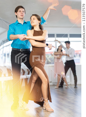 Young man practicing sensual bachata with brunette in dance class Young man practicing sensual bachata with brunette in dance class 113507579