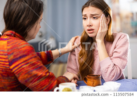 Woman complains to her friend about life while sitting at table with cups of tea Woman complains to her friend about life while sitting at table with cups of tea 113507584