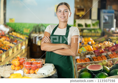 Positive and friendly store girl employee stands with arms crossed on chest and waits for customers Positive and friendly store girl employee stands with arms crossed on chest and waits for customers 113507598