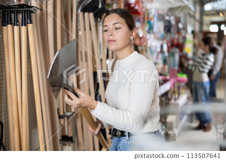 Young woman choosing shovel in store Young woman choosing shovel in store 113507641