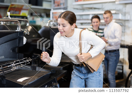 In store, girl inspects mobile grill, buys barbecue device 113507792
