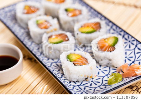 Uramaki. California salmon roll on wooden background. Salmon, avocado, rice, sesame. Uramaki. California salmon roll on wooden background. Salmon, avocado, rice, sesame. 113507856