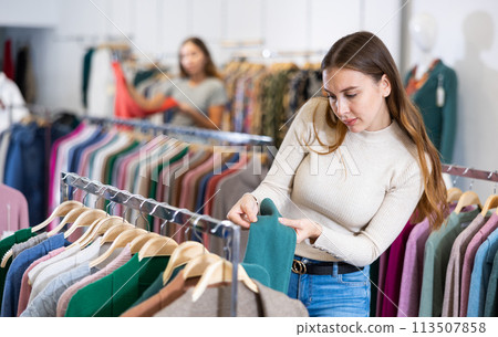 Smiling woman shows a stylish jacket in women clothing store Smiling woman shows a stylish jacket in women clothing store 113507858