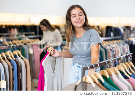 Customer deciding on jersey cardigan in women cloths shop Customer deciding on jersey cardigan in women cloths shop 113507876
