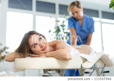 Young woman relaxing during professional back massage Young woman relaxing during professional back massage 113507948