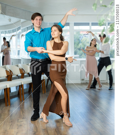 Young man practicing sensual bachata with brunette in dance class 113508018
