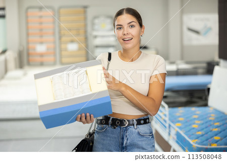Interested young girl examining mattress cross-section sample in furniture store Interested young girl examining mattress cross-section sample in furniture store 113508048