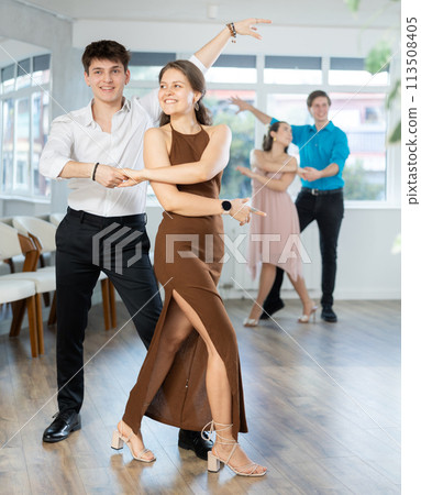 Couple in evening dresses enjoys pair dance tango, interacting with each other on floor 113508405