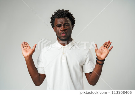Young Man Expressing Confusion and Surprise With Hands Up Against a Neutral Background 113508406