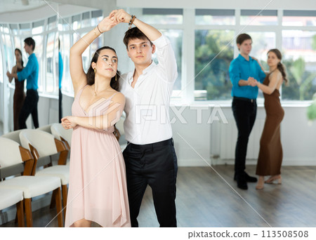Couple in evening dresses enjoys pair dance tango, interacting with each other on floor Couple in evening dresses enjoys pair dance tango, interacting with each other on floor 113508508