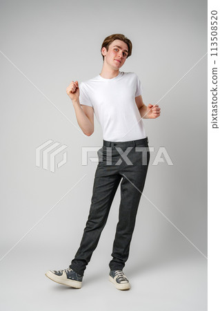 Young Man in Casual Attire Dancing Alone in a Studio Setting 113508520