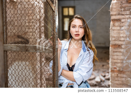Woman in knotted shirt and lace brassiere posing in ruined building 113508547