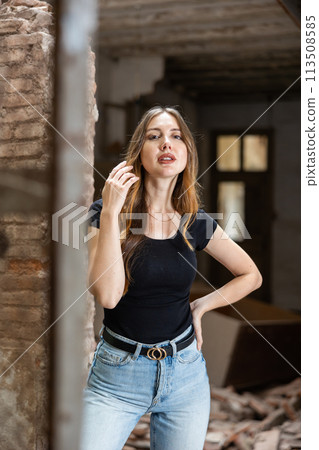 Young woman in black t-shirt and jeans posing in ruined building 113508585