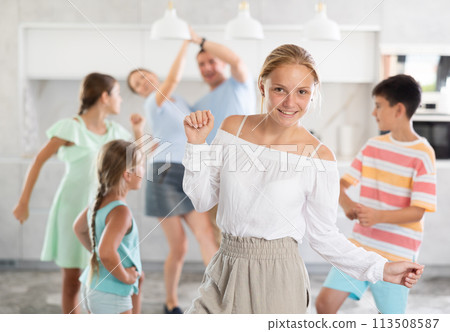 Portrait of a joyful teenager girl against the background of dancing large family 113508587