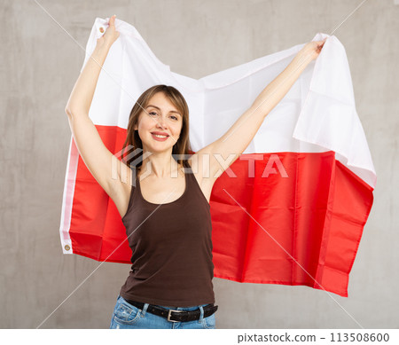 Smiling woman waving national flag of Poland on gray background Smiling woman waving national flag of Poland on gray background 113508600