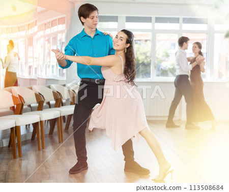 Couple in evening dresses enjoys pair dance tango, interacting with each other on floor Couple in evening dresses enjoys pair dance tango, interacting with each other on floor 113508684