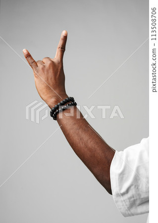 Hand Making the Rock N Roll Sign Against a Plain Gray Background Hand Making the Rock N Roll Sign Against a Plain Gray Background 113508706