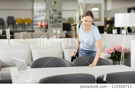 Woman buyer choose dining table desk in furniture store showroom Woman buyer choose dining table desk in furniture store showroom 113508711