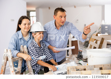 Parents and young son discussing work plan in construction site Parents and young son discussing work plan in construction site 113509017