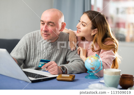 Happy married couple book a vacation tour on a laptop 113509019