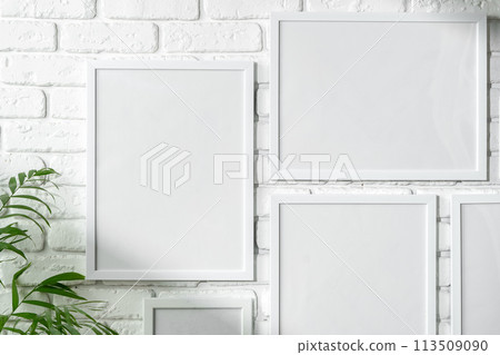 Varied Sized Photo Frames Displayed on a White Brick Wall 113509090