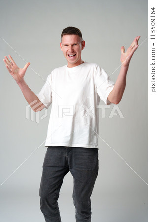 Portrait of surprised young man with shocked facial expression against gray background 113509164