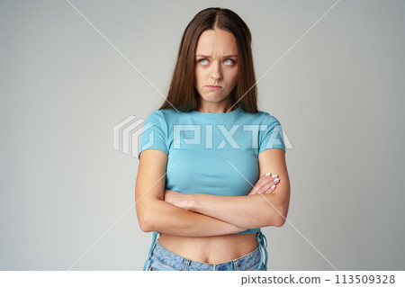 Portrait of sad displeased offended young woman in blue T-shirt on gray background Portrait of sad displeased offended young woman in blue T-shirt on gray background 113509328