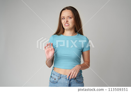 Young beautiful woman over gray background with disgusted displeased expression on gray background 113509351