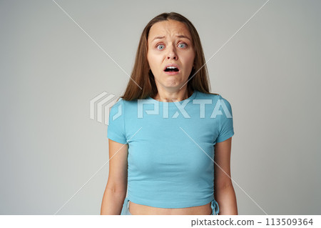 Emotional frightened young woman on gray background Emotional frightened young woman on gray background 113509364