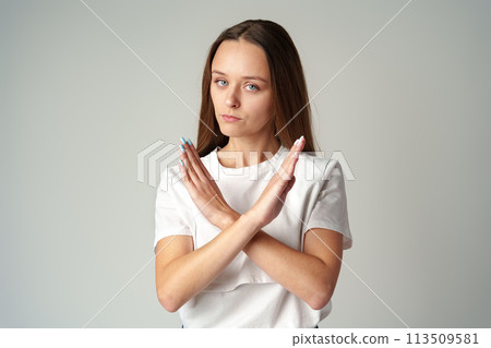 Young woman showing you crossed hands sign declining your request on gray background Young woman showing you crossed hands sign declining your request on gray background 113509581