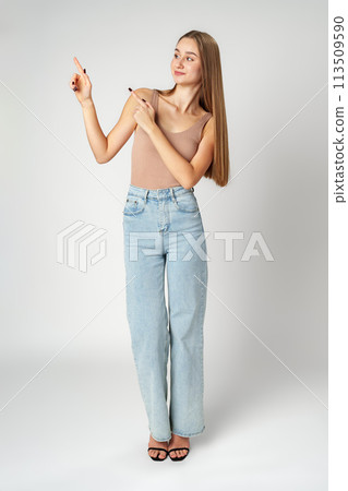 Young Woman in Tank Top Pointing at Something on gray background Young Woman in Tank Top Pointing at Something on gray background 113509590